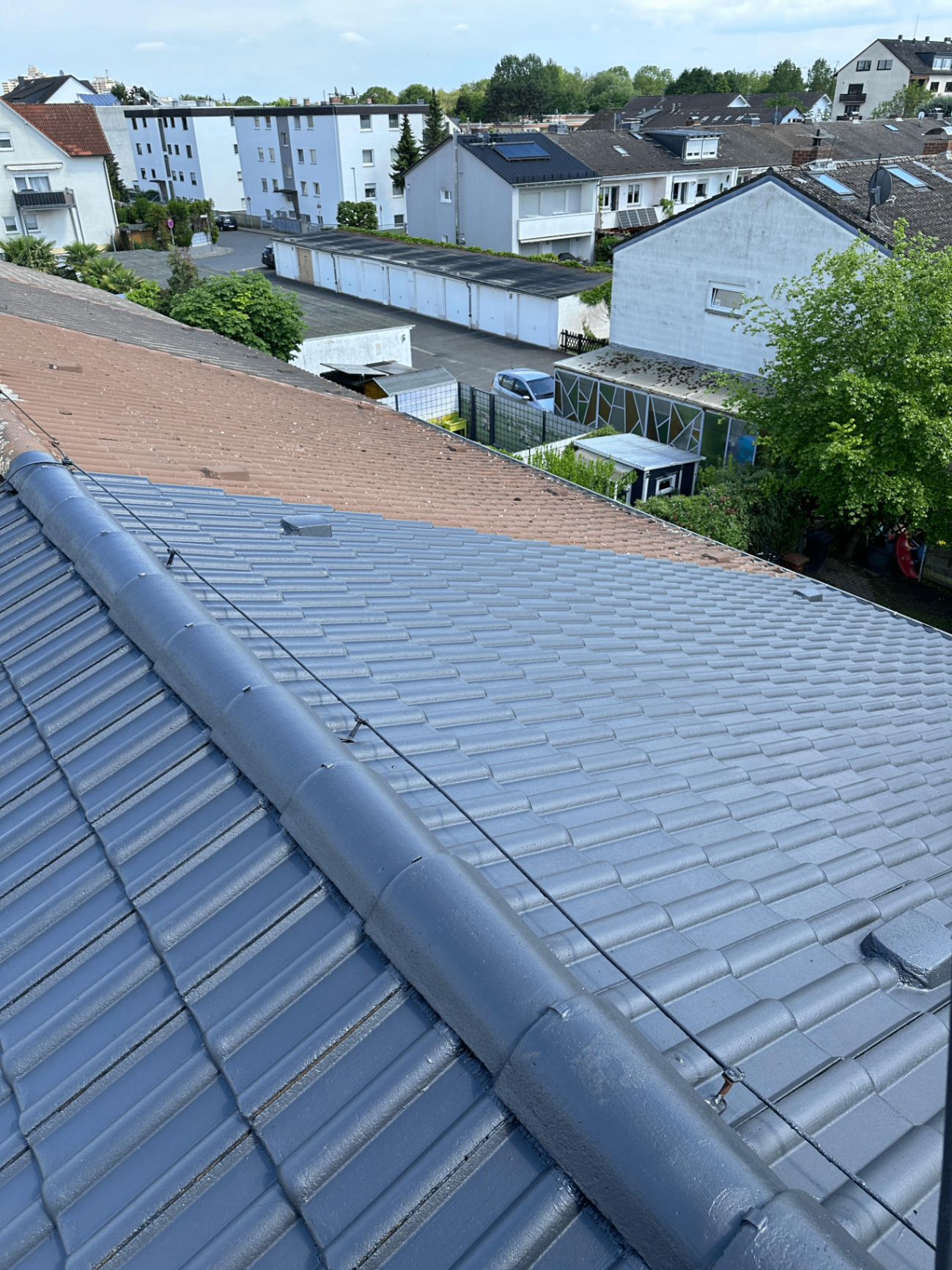 Dachbeschichtung in Hessen – Vergleich zwischen unbeschichtetem altem Ziegeldach und frisch beschichtetem, anthrazitfarbenem Dach